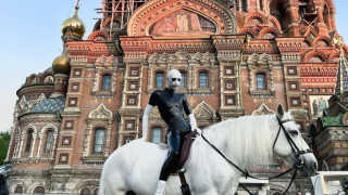 С боядисанo в бяло лице и носещ изцяло светъл ансамбъл