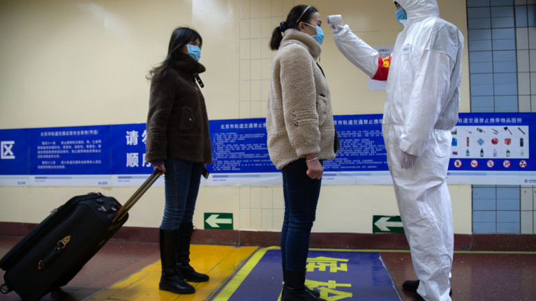 Медицински работник проверява температурата на хора в пекинското метро