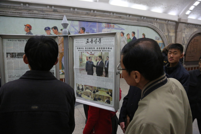 Хора, които четат вестник в метрото на Пхенян